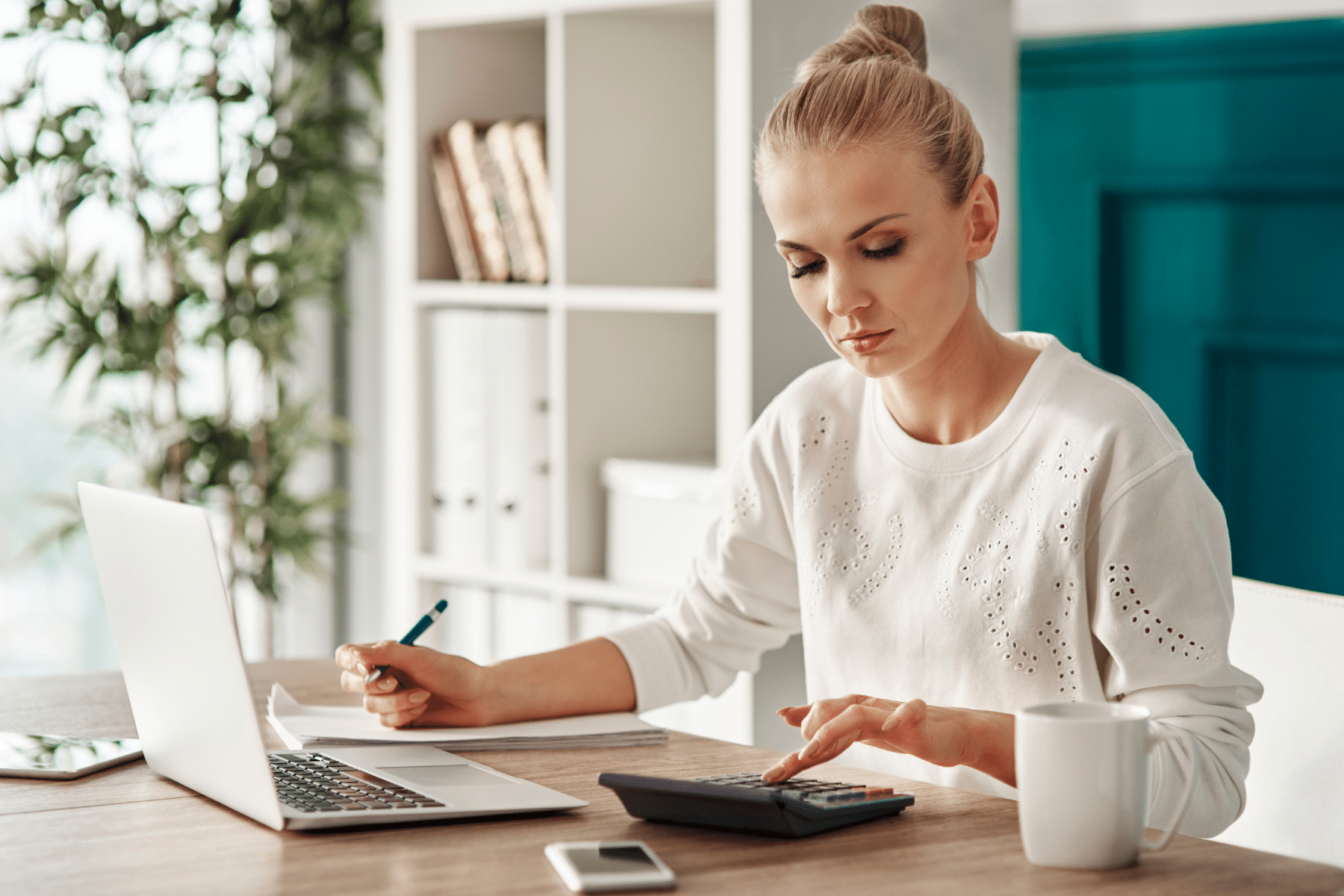 Woman budgeting at desk with laptop and calculator